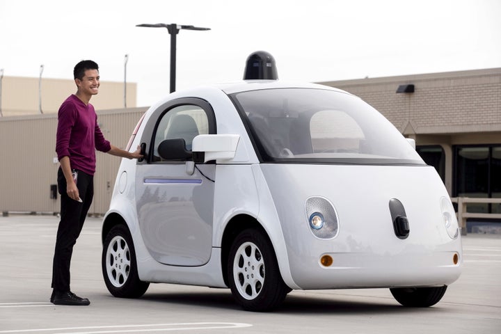 A Google employee stands next to a prototype of the company's self-driving vehicle during a media preview in Mountain Vi