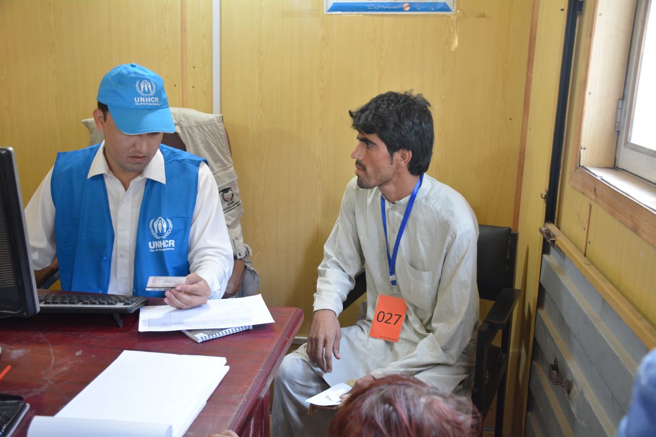 A UNHCR official checks the identification card of Musa Khan, 32, as he goes through the process of repatriation to Afghanistan.