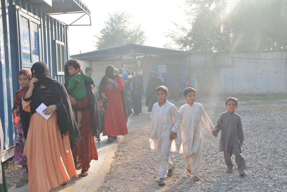 Children run around a UNHCR repatriation center in Peshawar as families wait in line to have their paperwork approved to
