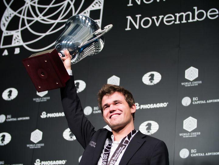 Magnus Carlsen hoists his trophy after successfully defending his world chess championship title