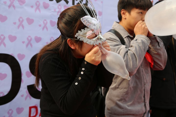 People blow to inflate condoms as they participate in a promotional event for AIDS prevention in Chongqing Municipality. 