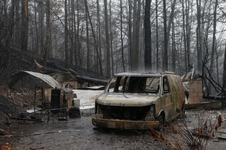 The remains of a van and home smolder in the wake of a wildfire Wednesday in Gatlinburg, Tennessee.