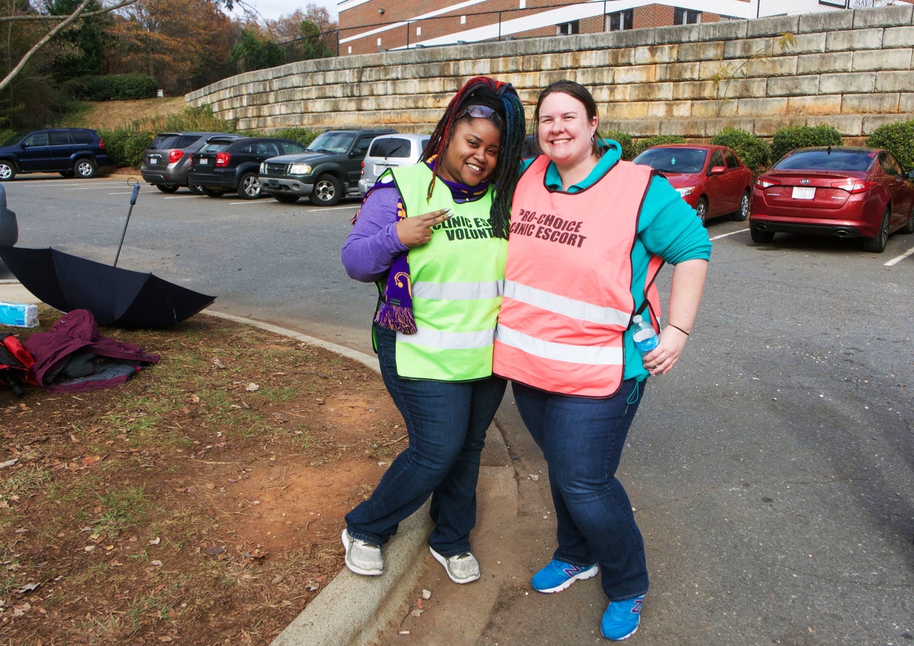 Two volunteer clinic escorts wait for patients outside the clinic. 