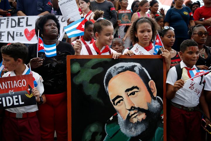 Schoolchildren wave Cuban flags while holding a portrait of Cuba's late President Fidel Castro as the caravan carrying Castro's ashes arrives in Santiago de Cuba, Cuba, December 3, 2016.
