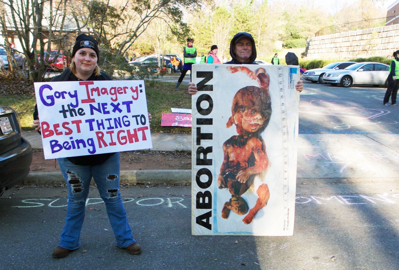 A pro-choice protester stands next to an anti-abortion protester at the entrance of APWHC Charlotte.