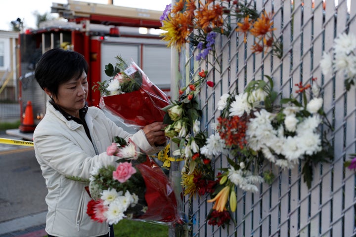 A woman places flowers at a makeshift memorial near the scene of a fire in the Fruitvale district of Oakland, California, Dec