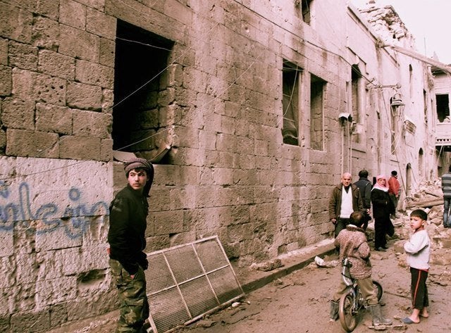 Residents survey the damage after a barrel bomb hit their street in opposition-held areas of Aleppo's Old City in January 201