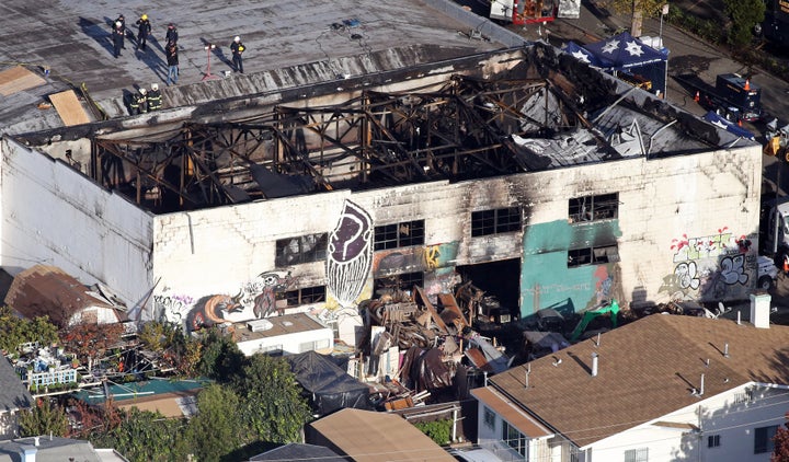 Recovery teams examine the charred remains of the two-story converted warehouse that caught fire, killing dozens, in Oakland,