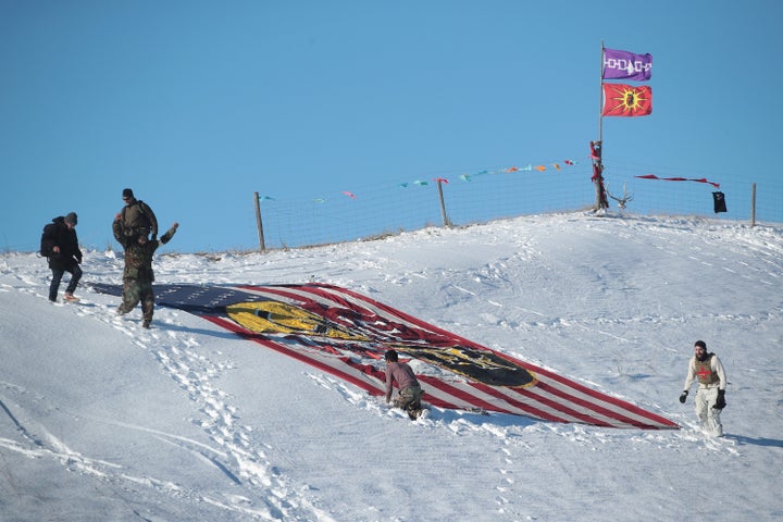 Military veterans place a flag that says 'one water' on a hillside above Oceti Sakowin Camp on the edge of the Standing Rock Sioux Reservation on December 4, 2016 outside Cannon Ball, North Dakota.