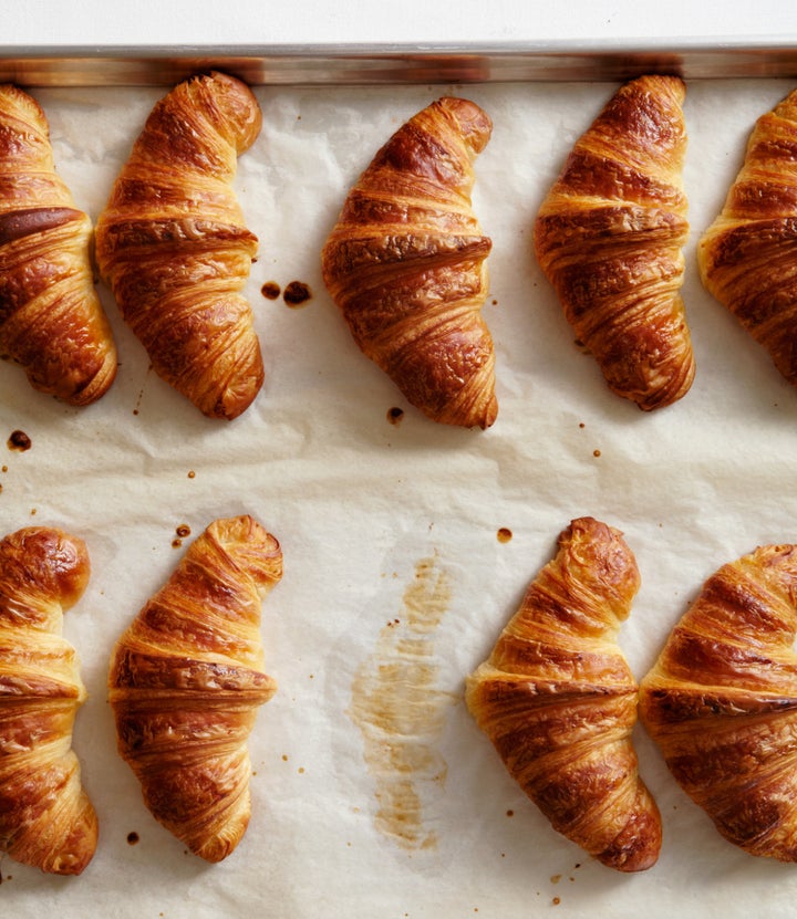 A line of croissants on a baking tray.