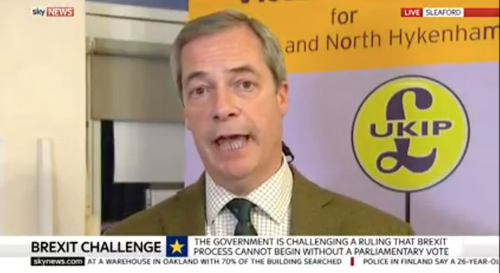 Farage with poster for Sleaford and North Hykeham campaign in background.