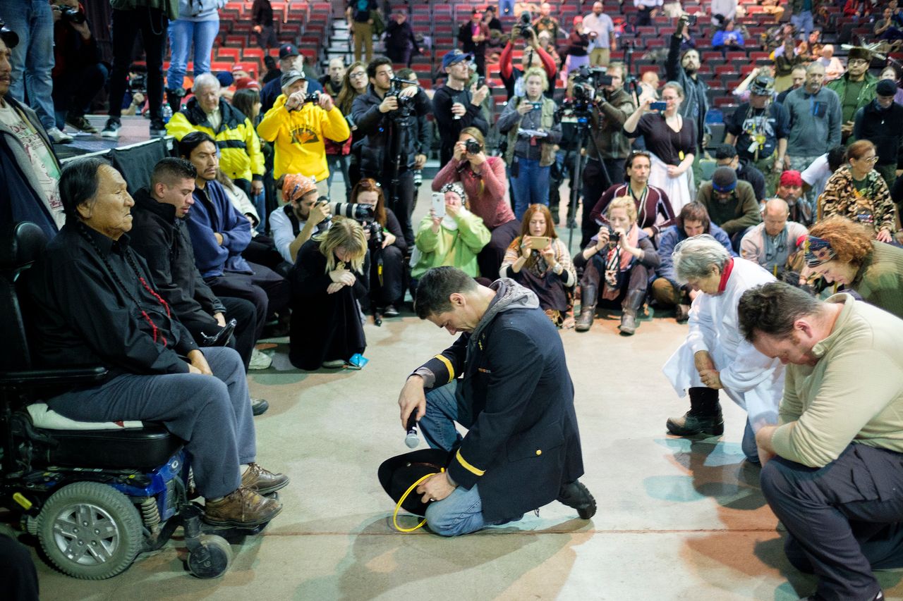 Wesley Clark Jr., middle, and other veterans kneel in front of Leonard Crow Dog during a forgiveness ceremony at the Four Prairie Knights Casino & Resort on the Standing Rock Sioux Reservation on Monday.