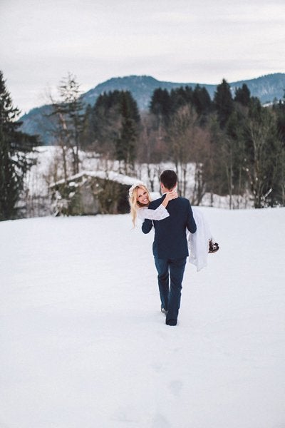 <p>This bride couldn’t look happier as her groom whisks her away, trekking through the snow.</p>