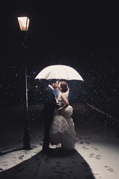 An umbrella not only shields this cute couple from the snow, but it acts as the perfect frame for their love.