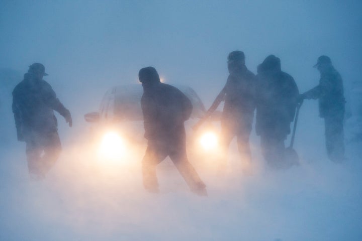 Several people attempt to free a vehicle from the snow in the Prairie Knights Casino and Resort parking lot during a blizzard