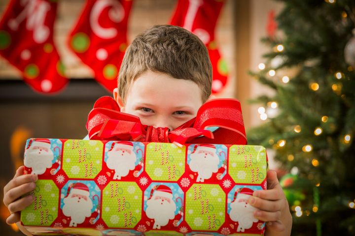 Caucasian boy holding Christmas gift Mike Kemp via Getty Images