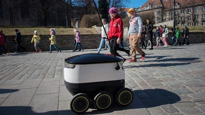 <p>Schoolchildren watch as a self-driving delivery robot developed by Starship Technologies drives past them in Tallinn, Estonia. The robots are arriving on sidewalks in two U.S. cities this month.</p>