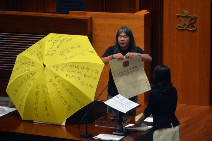Leung Kwok-hung of the League of Social Democrats rips up the "831 ruling," a decree from Beijing, before taking the Legislat