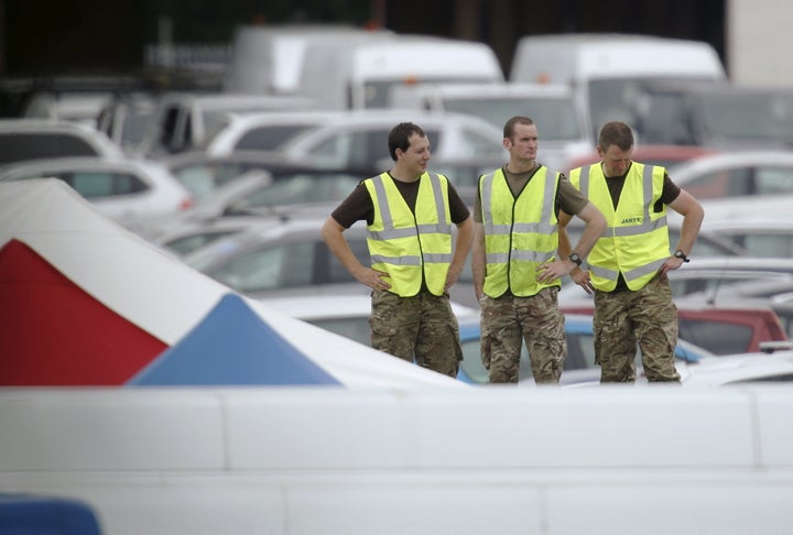 Military personnel prepare to work at the site of the airplane crash at the British Car Auctions lot next to Blackbushe Airport on August 1, 2015