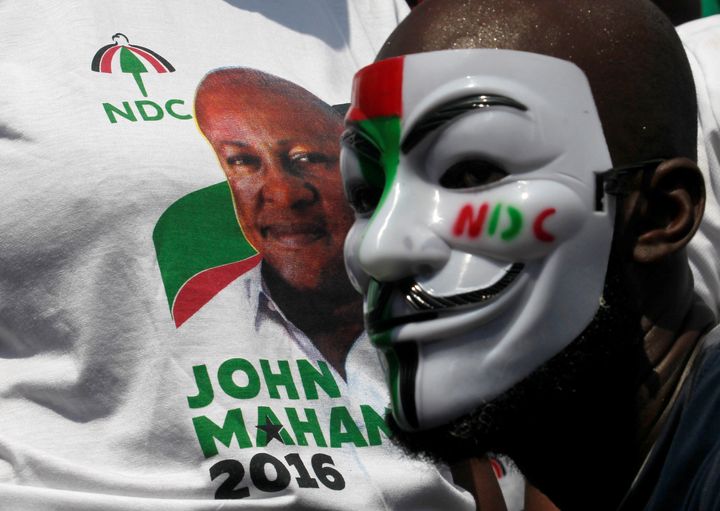 <strong>A masked supporter stands next to a picture of John Dramani Mahama, Ghana's president and National Democratic Congress (NDC) presidential candidate as he parades through a street during a presidential campaign rally in Accra, Ghana</strong>