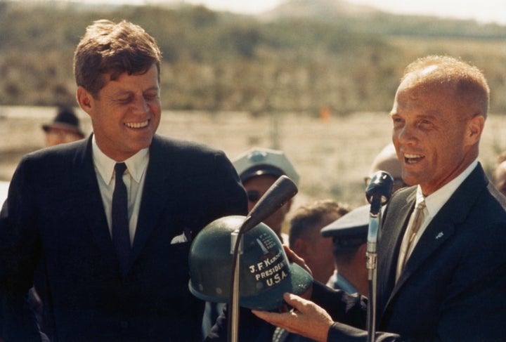Astronaut John Glenn hands a hard hat to President John F. Kennedy at Cape Canaveral in Florida. Several days before, Glenn b