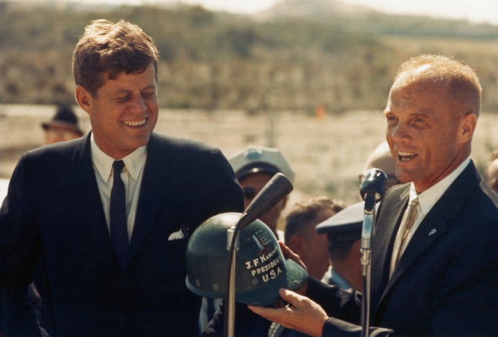 Astronaut John Glenn hands a hard hat to President John F. Kennedy at Cape Canaveral in Florida. Several days before, Glenn became the first person to orbit the Earth with the Mercury-Atlas 6 mission.