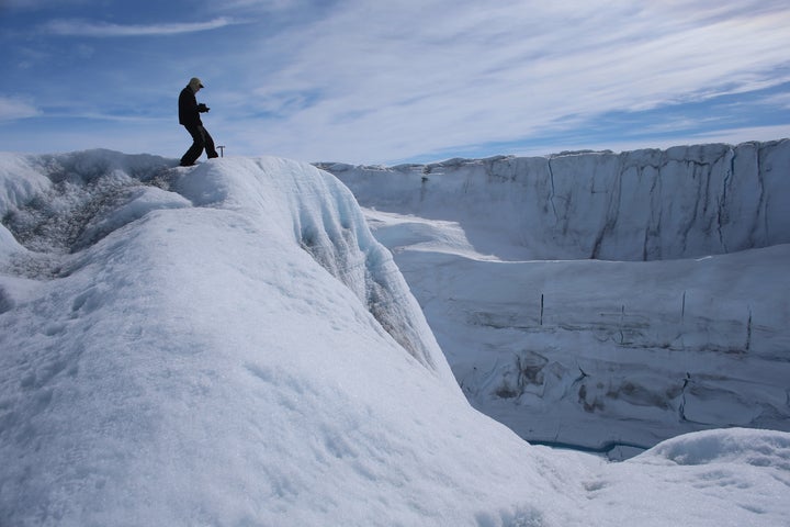 A researcher observes a canyon created over time by a meltwater stream on the Greenland's ice sheet, July 16, 2013.