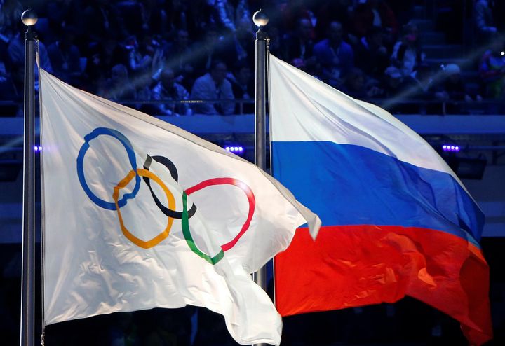 The Russian national flag (R) and the Olympic flag are seen during the closing ceremony for the 2014 Sochi Winter Olympics, Russia, February 23, 2014.