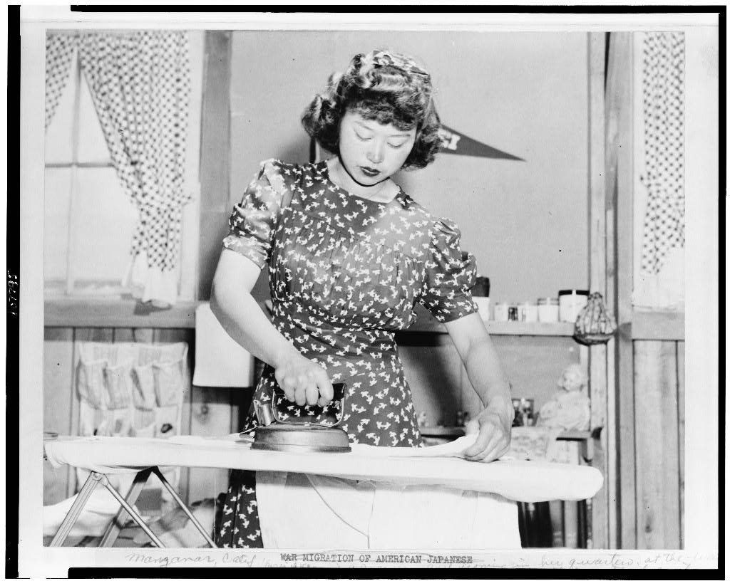 Ester Naite, an office worker from Los Angeles, is shown operating an electric iron in her quarters at a "War Relocation Authority center" in Manzanar, Calif.