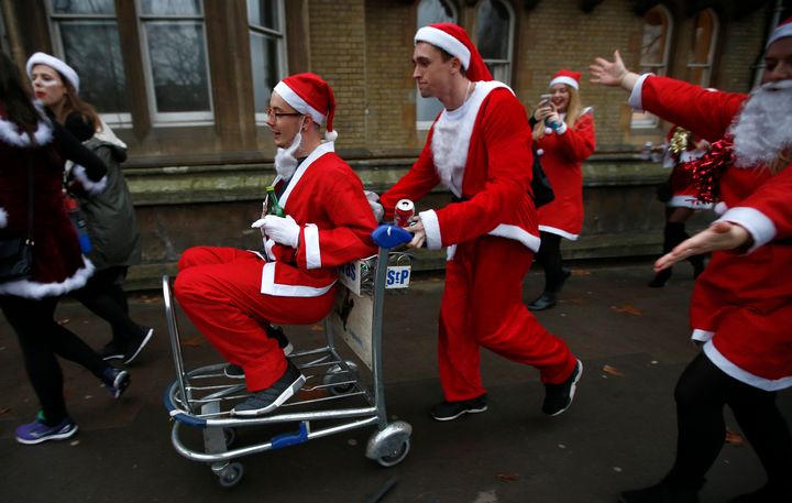 Revellers dressed as Santa push one another in a trolley.