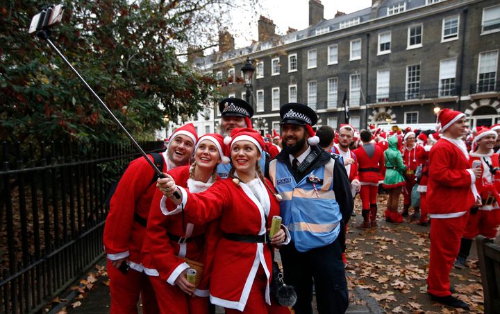 Groups dressed as Santas take a selfie with police.