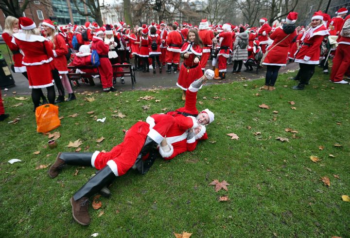 Revellers dressed in Santa suits wrestle outside Euston Station.