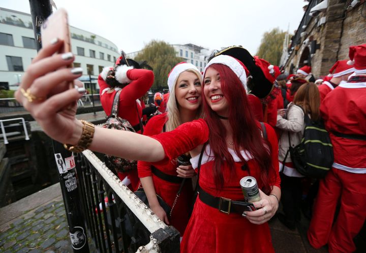 Two revellers dressed in Santa suits take a selfie before setting off from Camden in the Santacon Christmas parade.