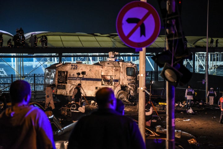 Forensic officers work as emergency officers walk with bodybags on the roof of the Vodafone Arena stadium at the site where a car bomb exploded killing 38