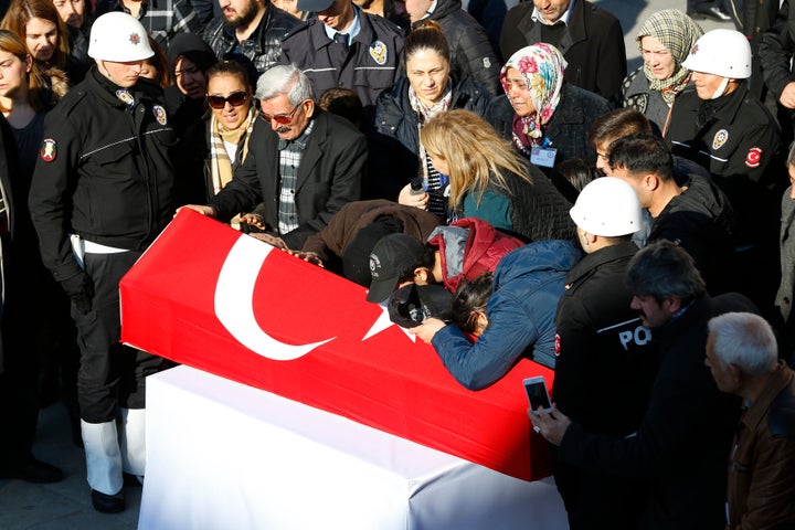Relatives mourn next to a coffin of a Turkish police officer killed in Saturday's blasts in Istanbul, Turkey, December 11, 20