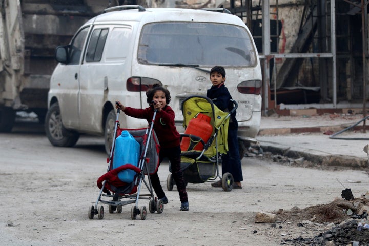 Children push containers in strollers as they flee deeper into the remaining rebel-held areas of Aleppo, Syria December 12, 2