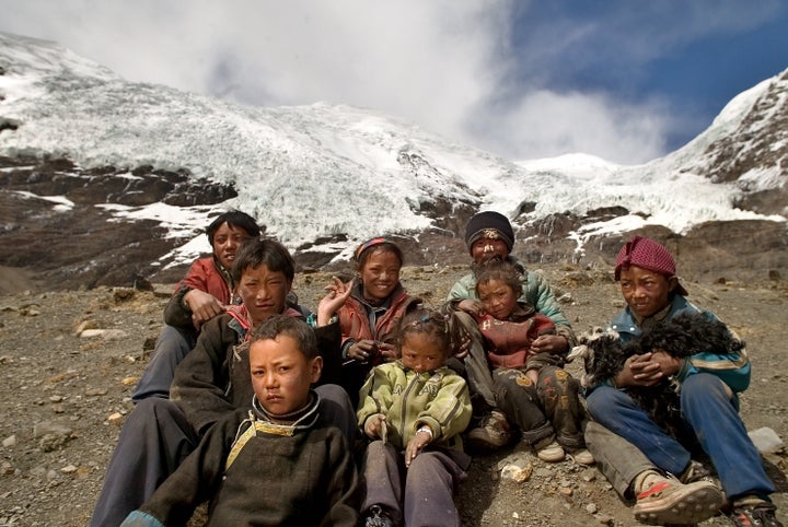 Local children sit in front of one of the glaciers on the Tibetan plateau.