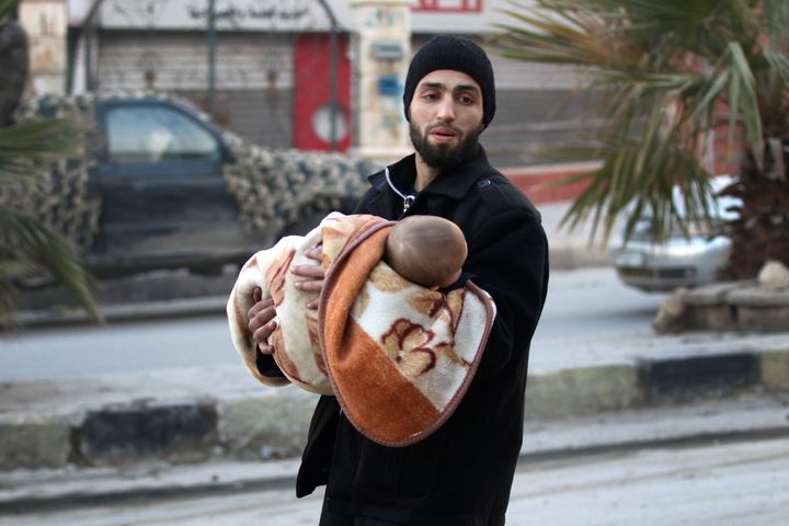 A man carries a child as he flees deeper into the remaining rebel-held areas of Aleppo