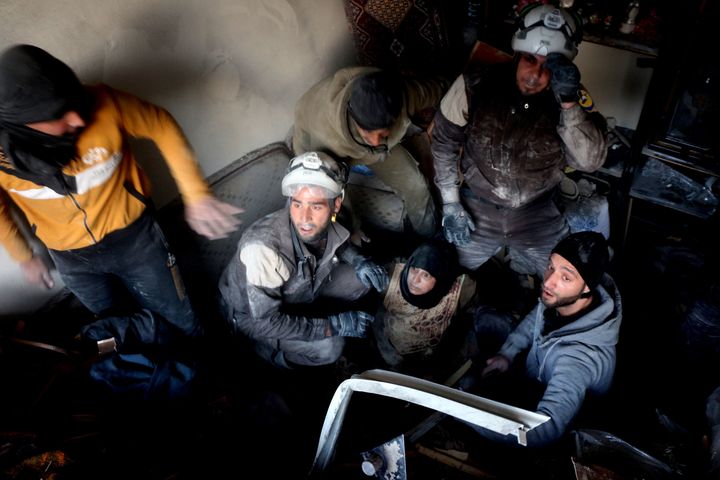 Members of the White Helmets rescue a woman from a bombed-out building