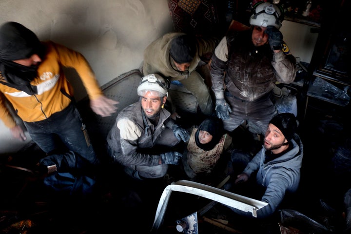 Members of the White Helmets rescue a woman from a bombed-out building