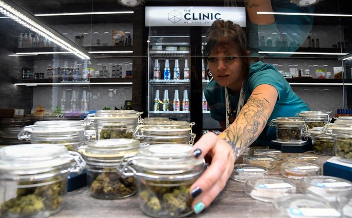 Holly Kinnel straightens out the display case at the new location for The Clinic, a marijuana retailer in Denver.