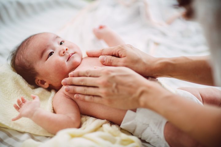 Mom giving her adorable baby massage while the baby lying on the bed after bathing Images By Tang Ming Tung via Getty Images