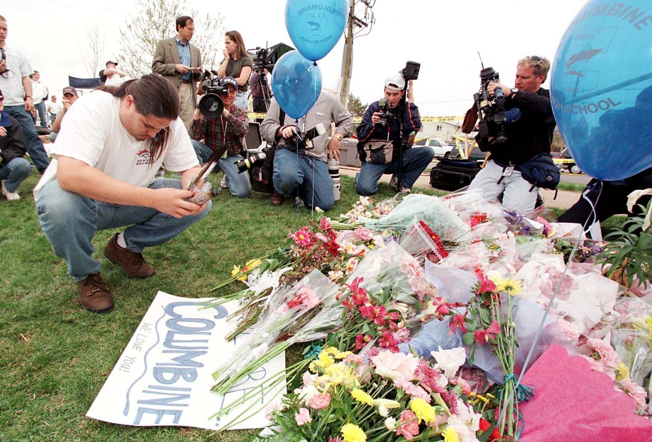 People and press gather at a memorial outside Columbine High School, the scene of a mass shooting on April 20, 1999.
