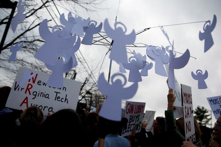 A protester outside National Rifle Association headquarters on the third anniversary of the Sandy Hook mass shooting carries a mobile with angels representing gun violence victims.