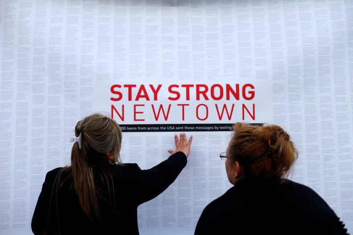 A woman touches a printout of messages from teenagers around the United States at a memorial for the victims of the Sandy Hook Elementary School shooting in Newtown, Connecticut, on Dec.18, 2012.