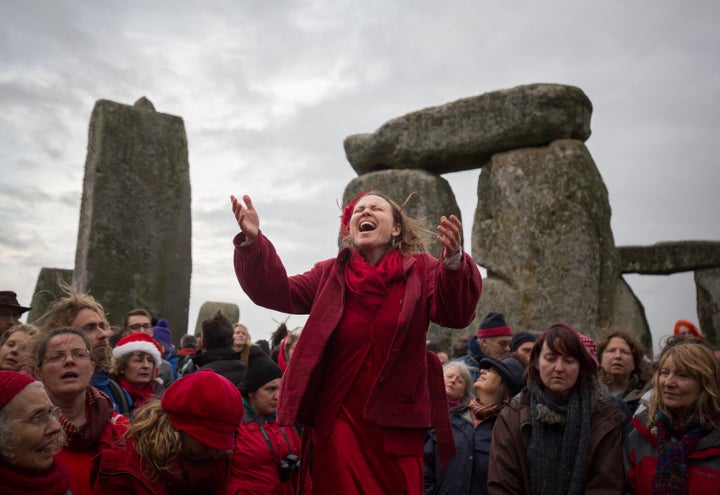 A woman leads the Shakti Sings choir as Druids, Pagans and revelers gather in the center of Stonehenge for a winter solstice ceremony on December 22, 2015.