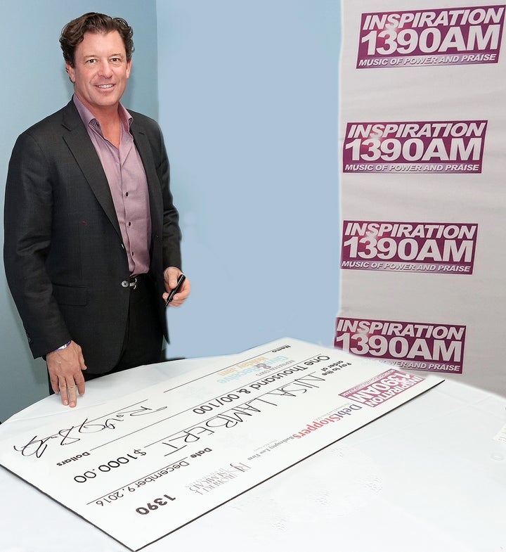 <p>Robert Semrad signing a donation check for his radio cash giveaway</p>