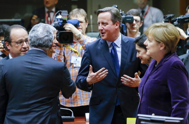 Cameron holds court with French President Francois Hollande and Merkel as a news cameraman captures the action