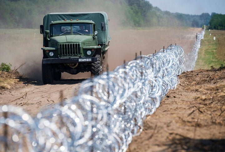 A Hungarian military truck passes a barbed-wire section of a 108-mile (175km) fence on Hungary’s southern border with Serbia near Kelebia, 110 miles (178 km) southeast of Budapest, Hungary, on Friday, Aug. 7, 2015.