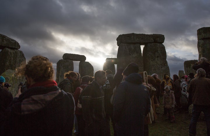 The sun peeks through clouds during a winter solstice ceremony at the ancient neolithic monument of Stonehenge near on December 22, 2015.